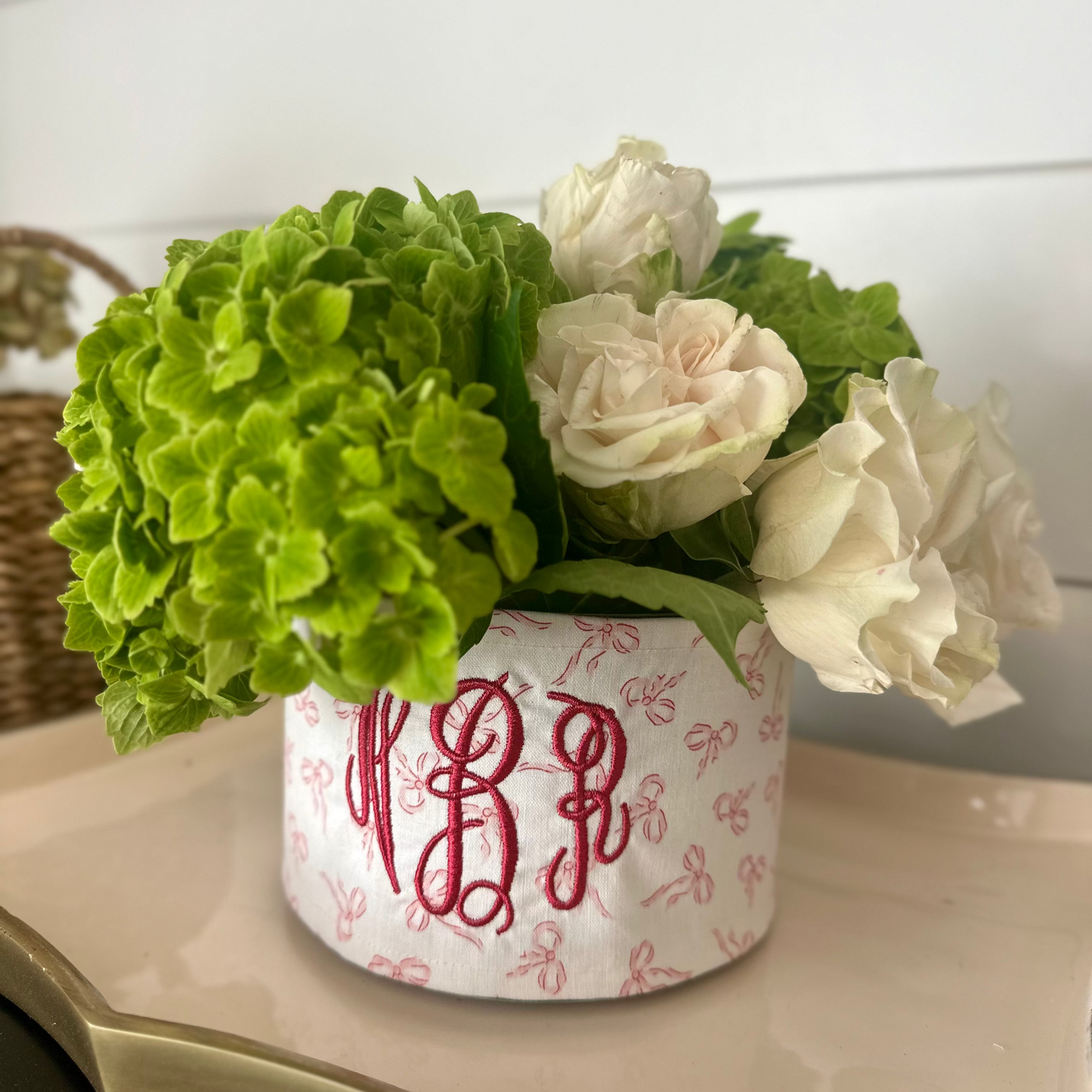 Decorative pot with monogram and flowers on a surface
